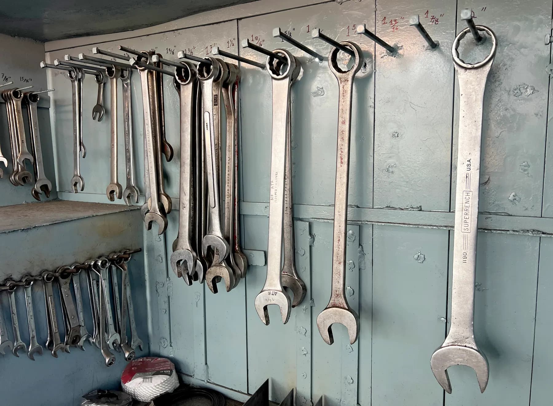 Wall of combination wrenches hung and labelled by size in a repair shop
